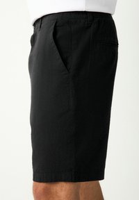 Shorts negros hechos de una tela texturizada, con bolsillos laterales, una cintura elástica y un bolsillo trasero con cierre de botón.
