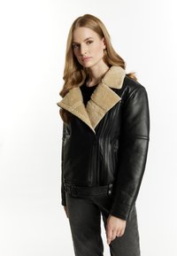 Giacca in pelle nera con colletto in shearling beige, chiusura con zip e tasche laterali. Presenta una vita con cintura e tessuto testurizzato.