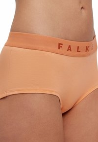 Perzikkleurige high-waisted slip met een FALKE-logo op de tailleband, gemaakt van gladde stof, met een slank ontwerp en naadloze randen.