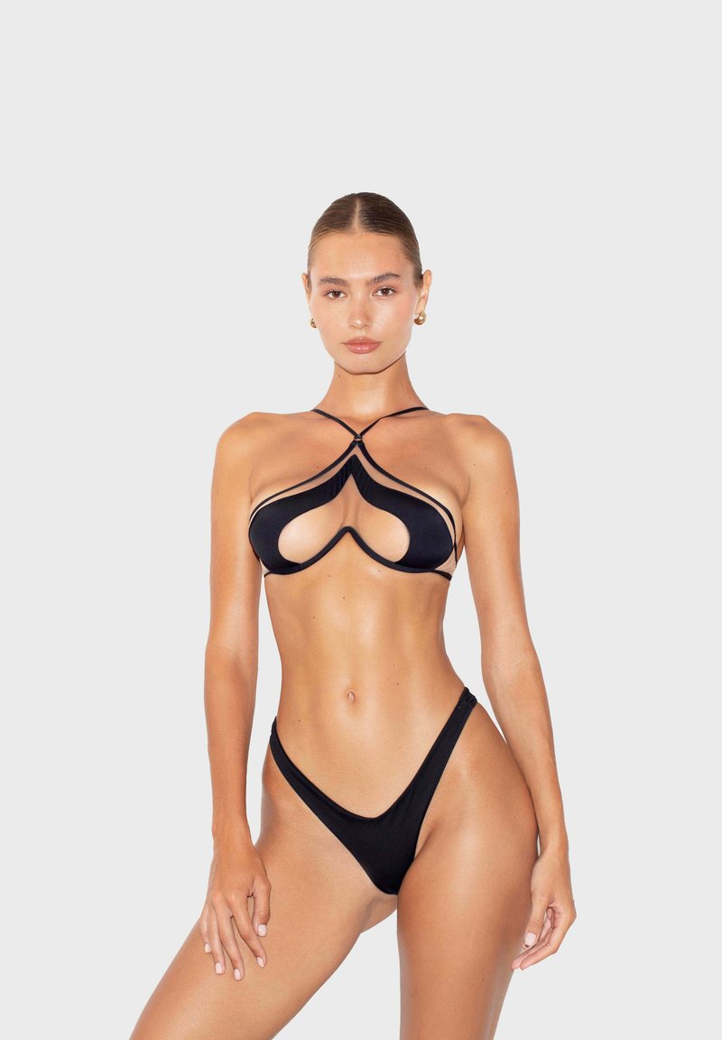 Bikini noir avec un design original de découpes et des fines bretelles. Le matériau est lisse et le bas a une coupe haute au niveau des jambes.