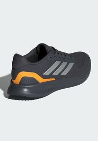 Schwarzer Sportschuh mit strukturiertem Obermaterial, grauen Akzenten und einem orangefarbenen Fersenbereich. Verfügt über eine gepolsterte Sohle und eine traditionelle Schnürung.
