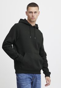 Black hoodie with a kangaroo pocket, featuring the word "TOKYO" embossed on the front. Made from soft fabric, with a drawstring hood.