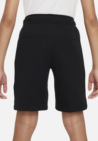 Svarta shorts gjorda av mjukt tyg med elastisk midja, med en enkel design och sydd fåll. Baksidan visar knälång längd.