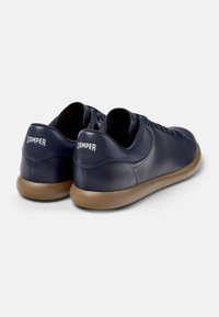 Scarpe in pelle blu scuro con una superficie liscia, forma arrotondata e suole in gomma marrone leggere. Marchio "CAMper" sul tallone.