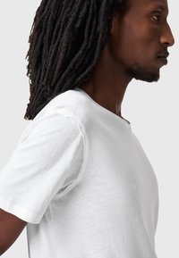 T-shirt bianco in cotone con scollo rotondo e maniche corte, caratterizzato da una vestibilità comoda e una superficie leggermente texturizzata.