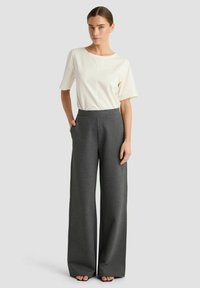 Grijze broek met brede pijpen, gemaakt van een zachte stof en met een hoge tailleband, gecombineerd met een crèmekleurig T-shirt met korte mouwen en een ronde hals.