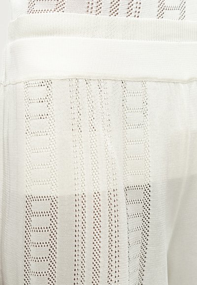 Λευκό πλεκτό ύφασμα με κάθετα και ορθογώνια ανοιχτά σχέδια και οριζόντια υφασμένη ταινία κοντά στην κορυφή.