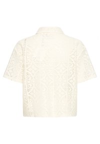 Krátky rukáv, krémová čipkovaná blúzka s geometrickými výrezmi a klasickým golierom, zobrazená zozadu.