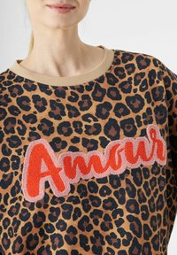 Sweater met luipaardprint in bruin en zwart, met een geborduurde rode tekst "Amour". Ribbelkraag in beige, zachte stof. Regular fit.