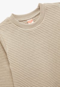 Suéter beige de canalé con cuello redondo y tejido texturizado. La etiqueta es visible en el cuello interior. Material suave y ligero.