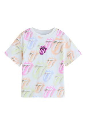 Biała koszulka z krótkim rękawem z wielobarwnymi logo języka Rolling Stones nadrukowanymi na całej powierzchni i różowym cekinowym logo na środku klatki piersiowej.