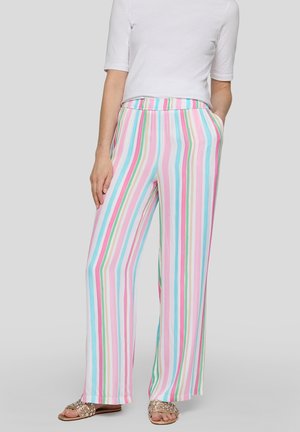 Person trägt weit geschnittene Hosen mit vertikalen Pastellstreifen in Pink, Blau, Grün und Weiß, kombiniert mit einem weißen Kurzarm-Top und Sandalen.
