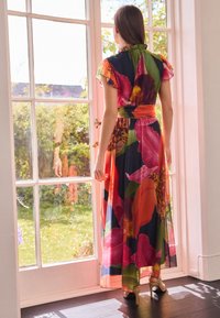 Maxikleid mit lebendigen Blumenmustern in Rot, Pink und Grün auf dunklem Hintergrund, mit kurzen, gerafften Ärmeln und einem gebundenen Taillenband.