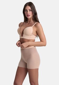 Set di lingerie beige con reggiseno a scollo profondo e spalline regolabili, abbinato a pantaloni alti, realizzato in tessuto morbido ed elastico.