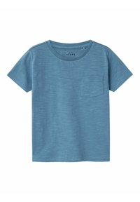 Camiseta de manga corta azul hecha de algodón suave, con escote redondo y un bolsillo en el pecho. Textura suave con un patrón sutil.