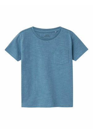 Camiseta de manga corta azul hecha de algodón suave, con escote redondo y un bolsillo en el pecho. Textura suave con un patrón sutil.