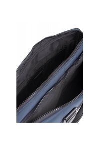 Blauwe en zwarte rits tas interieur met twee compartimenten met zwarte voering en een gladde textuur. Het twee-kleurige ontwerp benadrukt diepte.