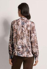 Blouse met lange mouwen, voorzien van een multi-kleurig abstract patroon in bruin, beige en grijs, met een knoopsluiting aan de achterkant en omgeslagen mouwen. Glad stoffen textuur.