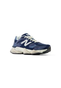 Navy blue athletic shoe with suede and mesh materials, white laces, and a prominent white logo on the side, featuring a cushioned sole.