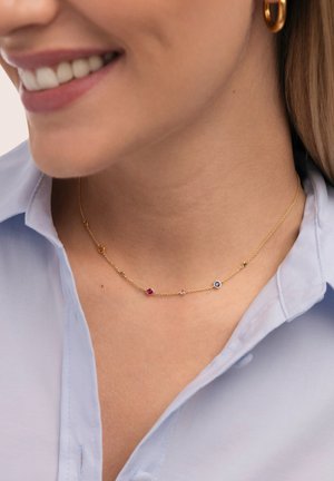 Collar de cadena de oro con piedras preciosas de varios colores, incluyendo rojo, azul y púrpura, con un diseño minimalista y eslabones delicados.