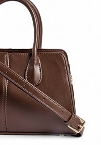 Brązowa skórzana torebka na ramię z podwójnymi uchwytami, regulowanym paskiem na ramię i widocznymi detalami szycia. Posiada elegancki, strukturalny design.