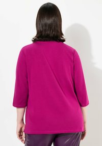 Magenta dlouhý rukáv top s kulatým výstřihem. Látka je hladká a rukávy mají tříčtvrteční délku. Jednoduchý design, bez vzorů nebo akcentů.