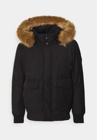 Schwarze Parkajacke mit einer tanfarbenen Kunstfellkapuze, vorderem Reißverschluss, zwei großen Fronttaschen und gerippten Bündchen.