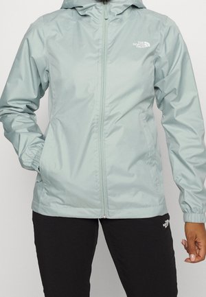 Ljust turkos regnjacka med dragkedja fram, justerbar huva och elastiska ärmslut. Har en logotyp på vänster bröstområde. Slät textur.