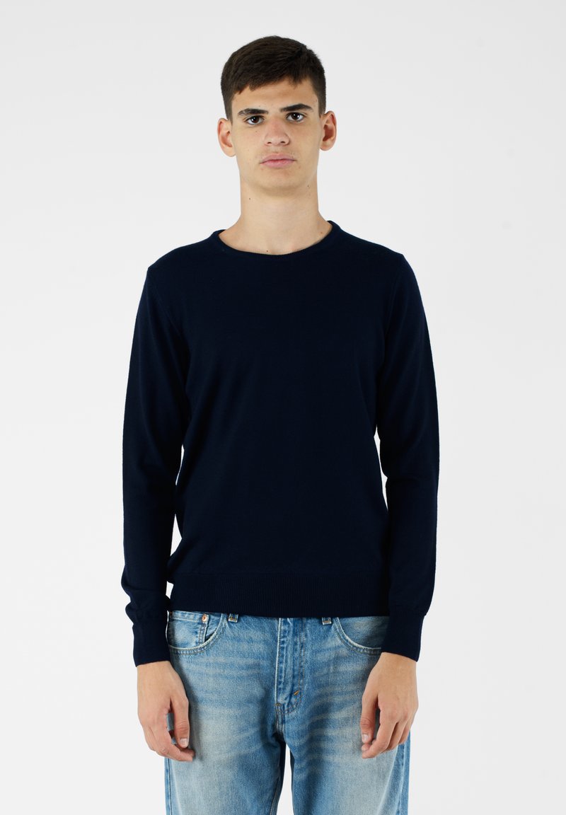 Maglione lavorato a maglia blu navy con collo rotondo, maniche lunghe e orlo a coste, abbinato a jeans azzurri. Tessuto liscio e vestibilità classica.