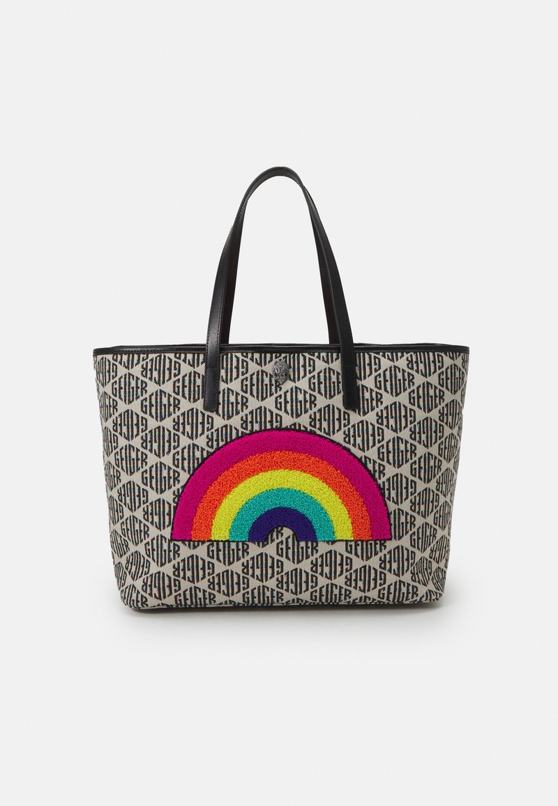 Sac fourre-tout beige avec un motif noir répétant le logo "Geiger" et des poignées noires, avec un patch arc-en-ciel coloré au centre avant.