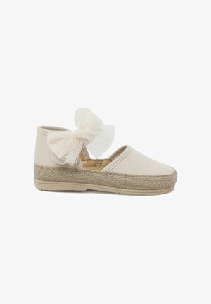 Chaussure espadrille en toile beige avec une semelle intermédiaire en jute tissé, ornée d'un grand nœud en tulle sur la bride et d'un design à bout rond.