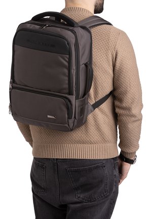 Zaino grigio scuro in nylon con schienale imbottito, spallacci regolabili e una tasca frontale con zip. Presenta un logo e dettagli metallici.