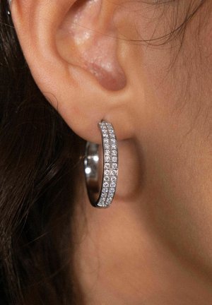 Zilveren hoopoorbel met een rij kleine, heldere rhinestones langs de buitenrand, een gladde textuur en een glanzende afwerking.
