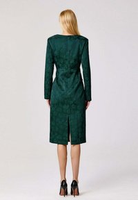 Robe à motifs floraux verts, à manches longues, longueur genou, fente au dos et silhouette ajustée. Confectionnée en tissu texturé à finition lisse.