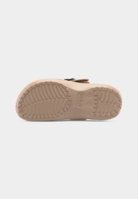 Μπεζ σόλα ενός σανδαλιού Crocs που δείχνει το μέγεθος 7 και το γράμμα "W" για γυναίκες, με υφή και σχέδιο πέλματος για καλύτερη πρόσφυση.