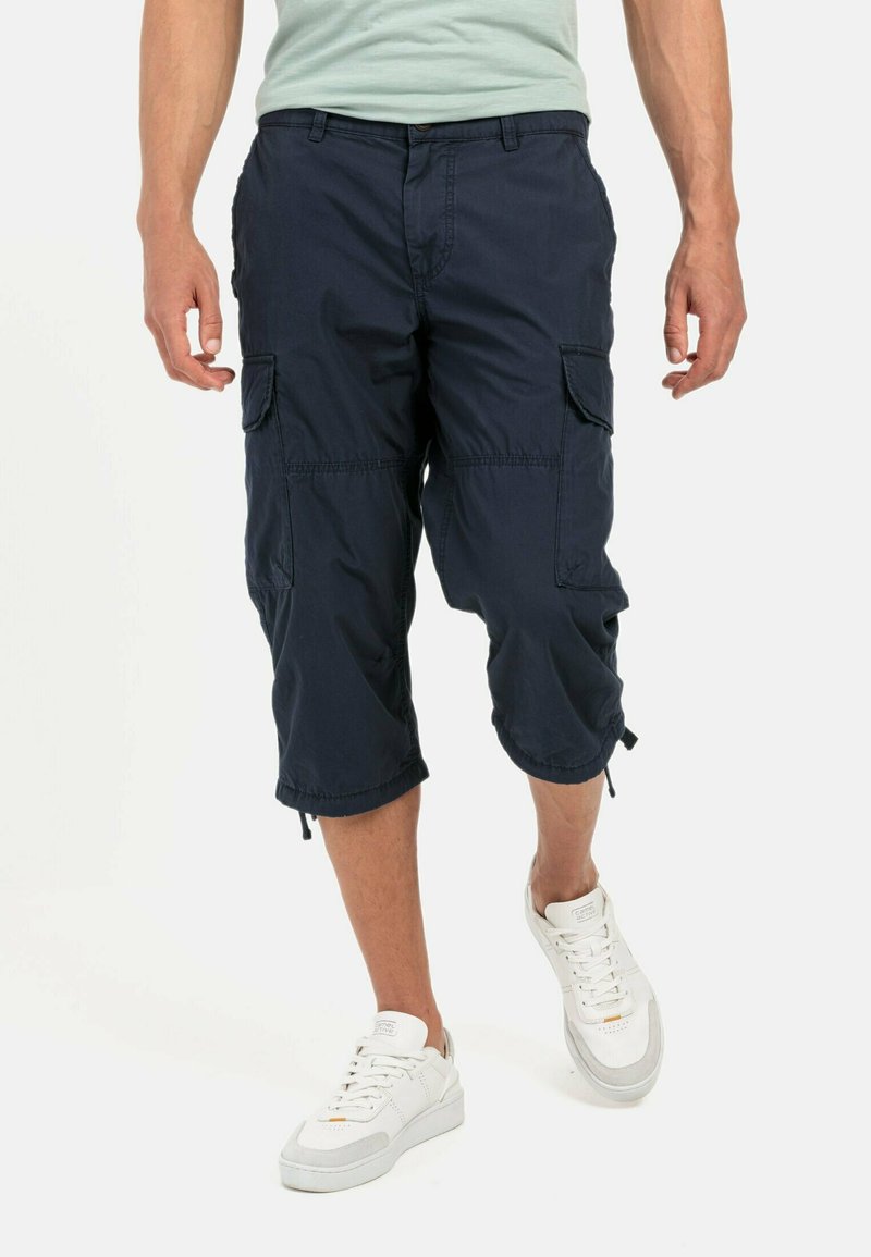Marine cargo shorts met meerdere zijzakken, een trekkoord aan de onderkant en een lichte, gestructureerde stof, gecombineerd met witte sneakers.