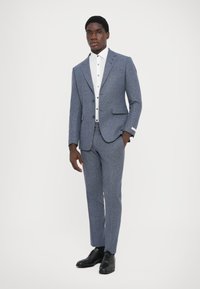 Blue wool suit with a fitted blazer and matching trousers, paired with a white button-up shirt and black leather shoes.