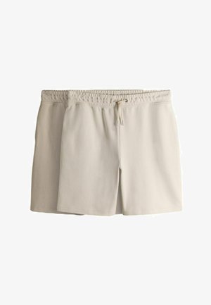 Kaks paari heledast beežist elastse vöökohaga lühikesi pükse paelaga, üks kihina teise taga valgel taustal.