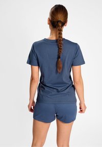 Granatowa bawełniana koszulka z krótkim rękawem i okrągłym dekoltem, w zestawie z pasującymi, krótkimi szortami z teksturowanej tkaniny, pokazana z tyłu z warkoczem.