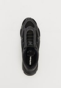 Chaussure de sport noire avec des panneaux en maille, un dessus texturé et des lacets ronds. Présente une semelle rembourrée et une marque "AIR MA" sur la semelle intérieure.