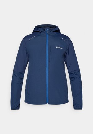 Keve navy blue takki, jossa on huppu, täydellinen etuvetoketju kontrastivärisessä sinisessä, joustavat hihansuut ja heijastavat yksityiskohdat.