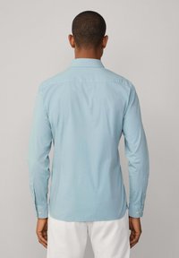 Lichtblauwe button-up shirt met een standaard kraag, lange mouwen en een afgeronde zoom. Glad textuur met enkelvoudige knoopmanchetten op de mouwen.