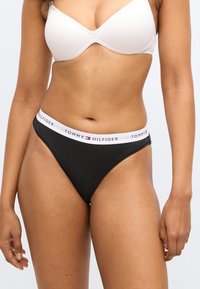 Slip bikini neri con una morbida fascia elastica in vita caratterizzata da una fascia bianca con logo. Tessuto dalla texture liscia. Design minimalista con vita bassa.