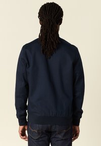 Marinblå bomberjacka i lätt tyg, med ribbade muddar och fåll, som har en ren och enkel design utan synliga logotyper eller dekorationer.