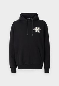 Hanorac negru cu glugă ajustabilă, buzunar frontal tip kangaroo, manșete cu motiv cu dungi și un broderie mare „K” în alb și bej pe piept.