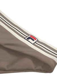Zbliżenie na szarą tkaninę sportową z białym elastycznym paskiem w pasie z czarno-białymi paskami oraz naszywką z logo w kolorze czerwonym i granatowym.
