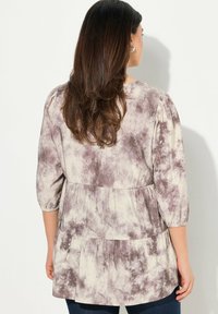 Top a maniche tre quarti in crema e taupe, caratterizzato da un design a strati con un motivo testurizzato e screziato e dettagli di vita arricciati.