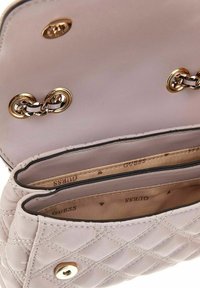 Sac à main en cuir rose clair avec texture matelassée, équipé de quincaillerie dorée, d'une fermeture à clasp et de deux compartiments intérieurs doublés de tissu beige.