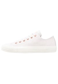 Baskets basses en daim blanc avec œillets en or rose, tissu texturé, semelle en caoutchouc et design caractéristique de bout renforcé. Style minimaliste et moderne.