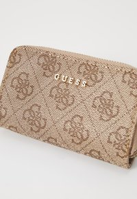 Brązowy portfel na zamek z wzorem, wykonany z teksturowanej tkaniny. Posiada złote logo "GUESS" oraz powtarzający się wzór monogramu.